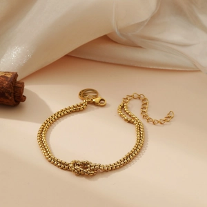 Double-layered gold stainless steel chain bracelet with a knot design on silk and wood