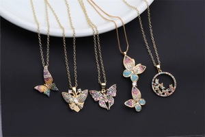 Detail view of five gold butterfly pendants featuring colorful rhinestones on black surface