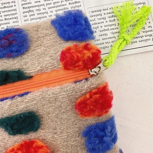 Detail of colorful knitted pouch showing texture, orange zipper, and neon green puller