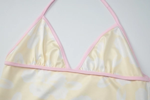 Detail of floral halter bikini top in light yellow with pink trim and white flower print