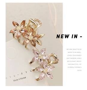Close-up of small floral crystal hair claws in champagne and pink with rhinestone details