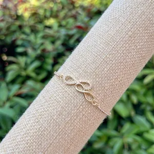 Detailed view of 18K gold infinity bracelet with sparkling pave zircon on display