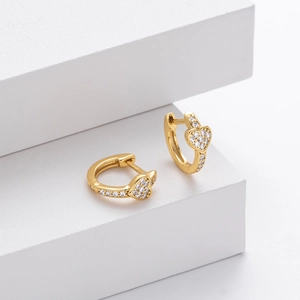 Macro shot of gold-plated S925 silver huggie earrings with heart-shaped pave-set zircons