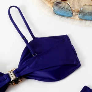 Detail of dark blue bikini top with adjustable straps and golden floral petal buckle