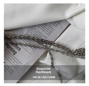 Close-up of polished silver metal chain strap with industrial finish on the bag