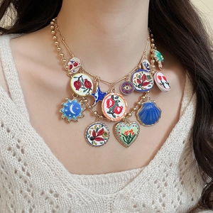 Close-up of bohemian gold chain necklace featuring colorful enamel pendants on model