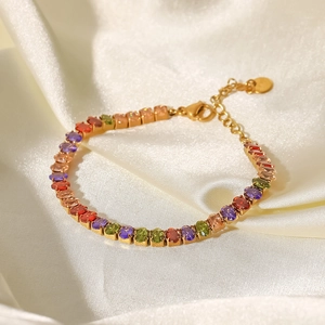 Nahaufnahme von buntem Edelstein-Tennisarmband mit 18K Goldbeschichtung auf weißer Seide