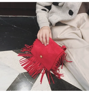 Close-up of a red suede kids crossbody bag featuring long fringes and a gold snap button