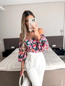 Close-up of a floral off-shoulder crop top paired with high-waisted belted white pants