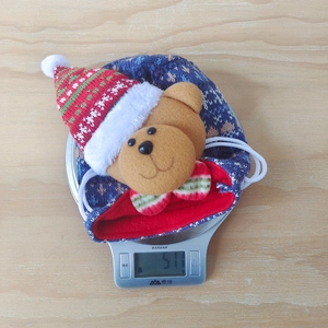 Detailed view of a blue knitted Christmas bear gift bag being weighed on a scale