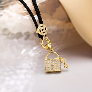 Macro detail of gold-plated heart lock pendant with zircons on black braided cord