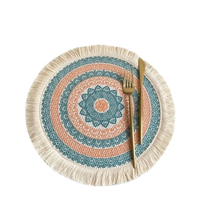 Mandala style woven round placemat with blue and orange fringe tassels on white background