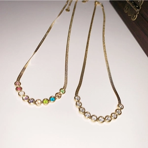 Flat gold snake chain necklace detail with bezel-set colorful and clear zircon stones