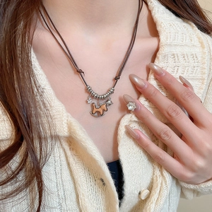 Detail of wooden rocking horse pendant necklace with metal star on beige sweater