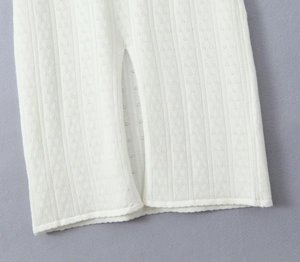 Détail de l'ourlet de la robe en tricot blanc montrant la fente et la texture du tissu