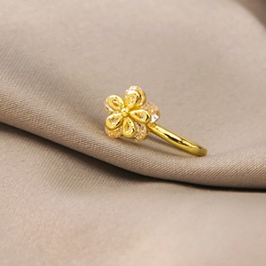 Macro detail of gold flower non-pierced nose clip with sparkling cubic zirconia on beige fabric
