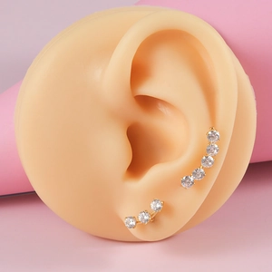 Gold plated stainless steel ear studs with round clear zircons on a pink background