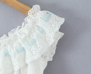 Detail of white lace embroidery with blue ribbon lacing on a wooden hanger