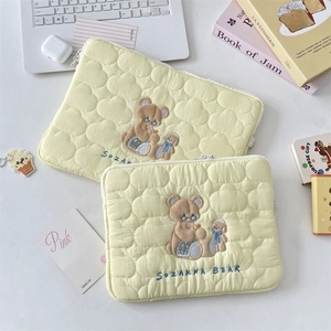 Detalle de funda acolchada para portátil con diseño de nubes y bordado de osito con cremallera