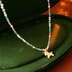Detail of white enamel dog pendant with pearls and colorful beads in a velvet box