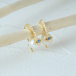 Macro view of 925 silver evil eye earrings with large pearls and blue crystals