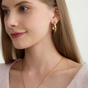 Élégantes boucles d'oreilles créoles C en acier titane doré portées par modèle