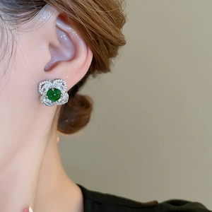 Close-up of vintage flower stud earring with green gemstone and pavé crystal petals