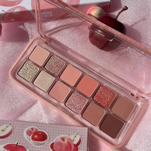 Detail of 12-color eyeshadow palette with matte and glitter shades on pink fabric