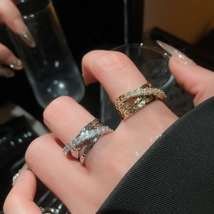 Detailed view of triple-layered crisscross rings with zircons and hammered metal texture