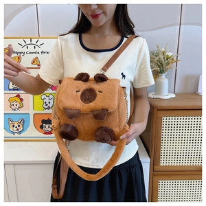 Brown plush Capybara crossbody bag shown on model in a cozy indoor setting
