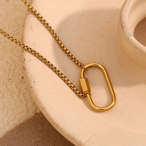 Detailed macro of 18K gold plated box chain necklace with oval carabiner lock on stone tray