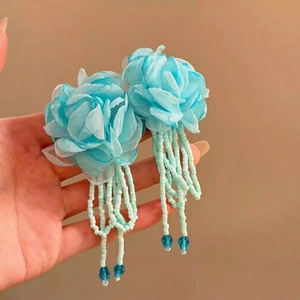 Detail of light blue fabric flower earrings with long beaded tassels and crystal drops