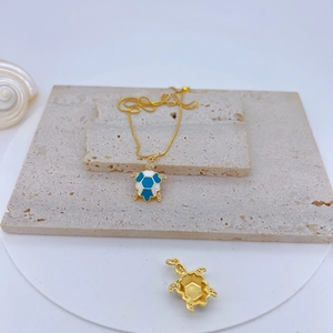 Gold turtle necklace with blue enamel shell and crystals on a textured stone base