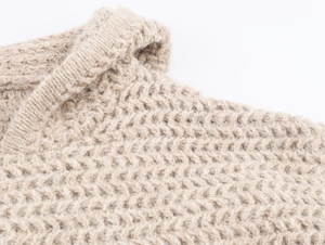 Close-up of beige chunky knit texture and shoulder details of hooded pullover sweater