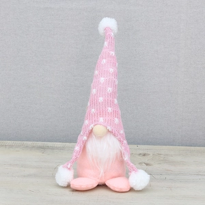 Gnome de Noël rose en peluche avec bonnet en tricot à pois sur surface bois