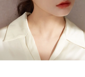 Detail of elegant cream satin shirt collar with smooth texture and silk-like finish