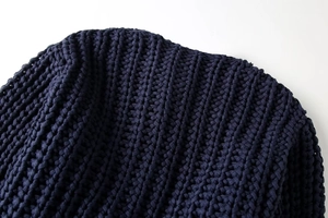 Gros plan d'un pull en maille épaisse bleu foncé montrant la texture du tissage