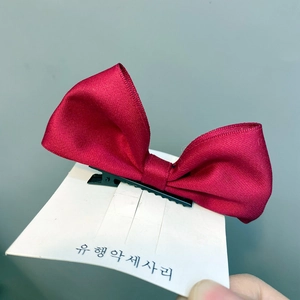 Detail einer roten Haarklammer aus Ripsband mit einer schwarzen Entenschnabelklemme