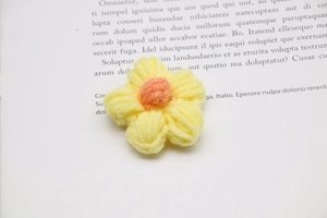 Detailed view of a yellow knitted milk cotton flower with orange center for DIY crafts