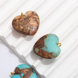 Détails macro de pendentifs cœur en résine avec texture pierre naturelle et boucles dorées