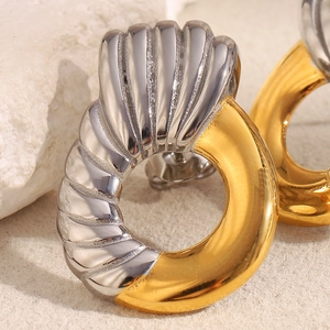 Detailed view of bicolor silver and gold twisted spiral earrings on a stone background