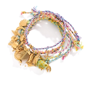 Close-up of woven ocean bracelets with golden marine charms like shells and dolphins