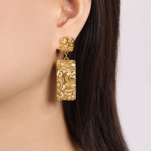 Golden titanium steel square earrings with irregular lava texture on female model