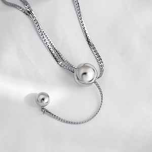 Detailed macro view of silver snake chain with polished metal spheres on white silk