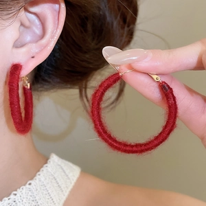 Detail of burgundy wool-wrapped hoop earring showing fuzzy texture and gold-plated hook