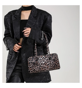 Leopard print handbag detail featuring sleek handle and heart-shaped charm accessory