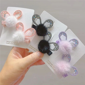 Detailed view of sparkling rhinestone bunny ear hair clips with soft faux fur pom-poms