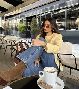 Street style shot of a woman wearing a yellow round neck jacket and blue denim pants
