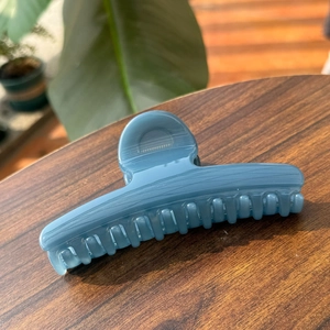 Detailed shot of a blue marble texture hair claw clip on a rustic wooden table surface