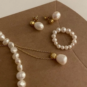 Flat lay of vintage pearl jewelry set including ring, earrings and necklace on kraft paper
